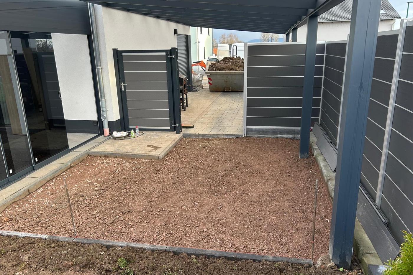 Vorbereitete Gartenfläche unter einem Carport mit gesetzter Randeinfassung