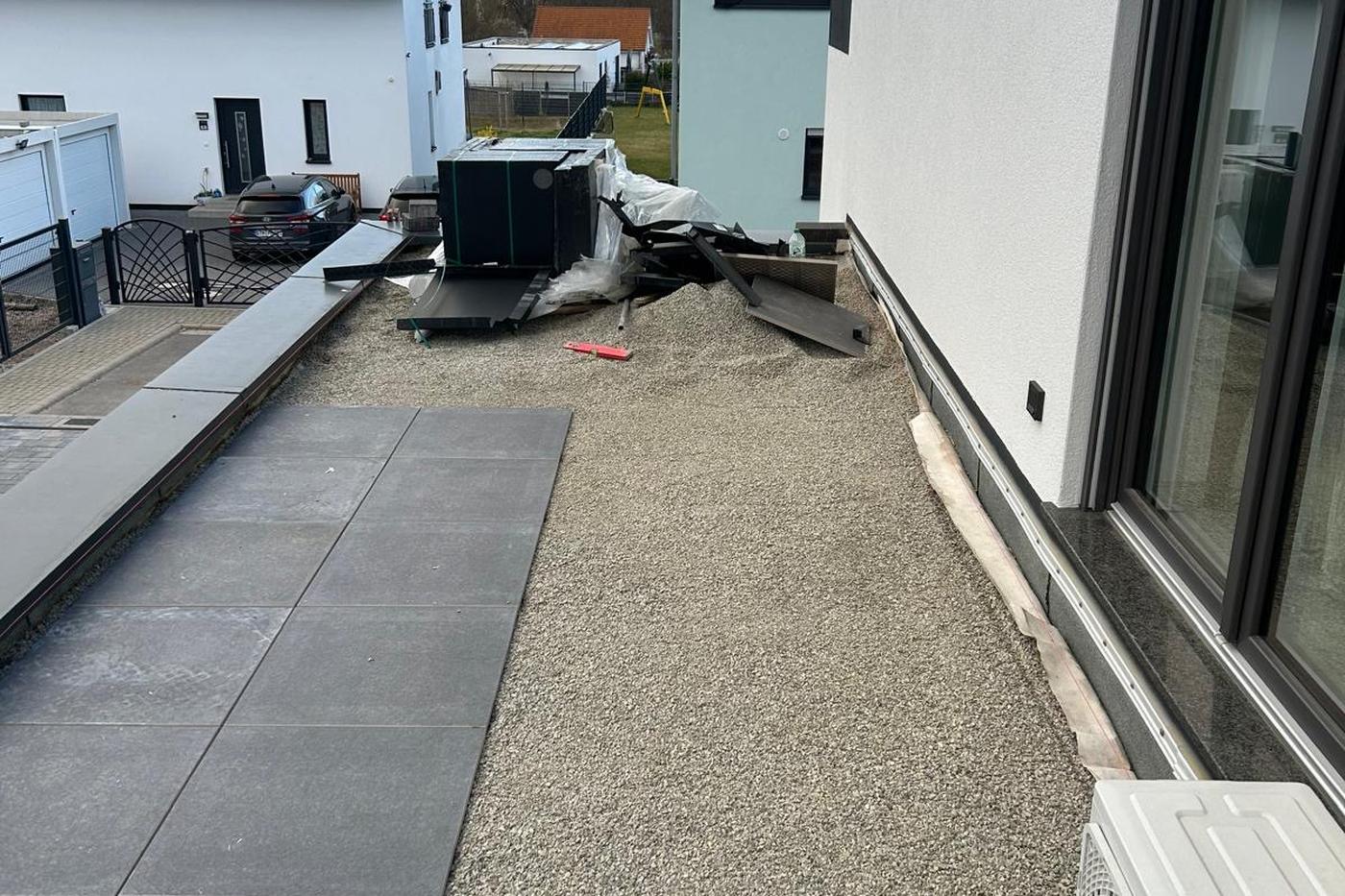 Splittfläche und Plattenweg entlang eines Neubaus, Außenanlage im Aufbau