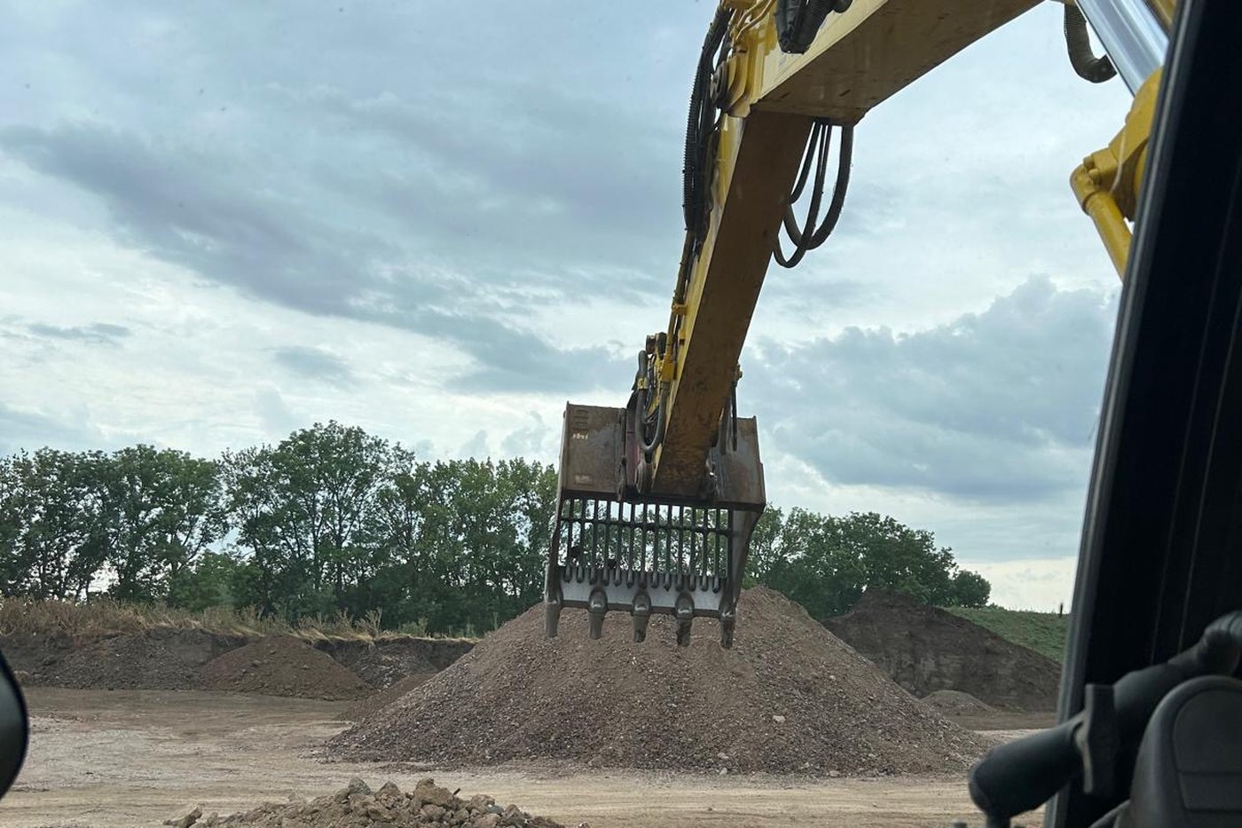 Blick aus der Baggerkabine auf den Sortiergreifer und die aufgesetzten Bodenmieten