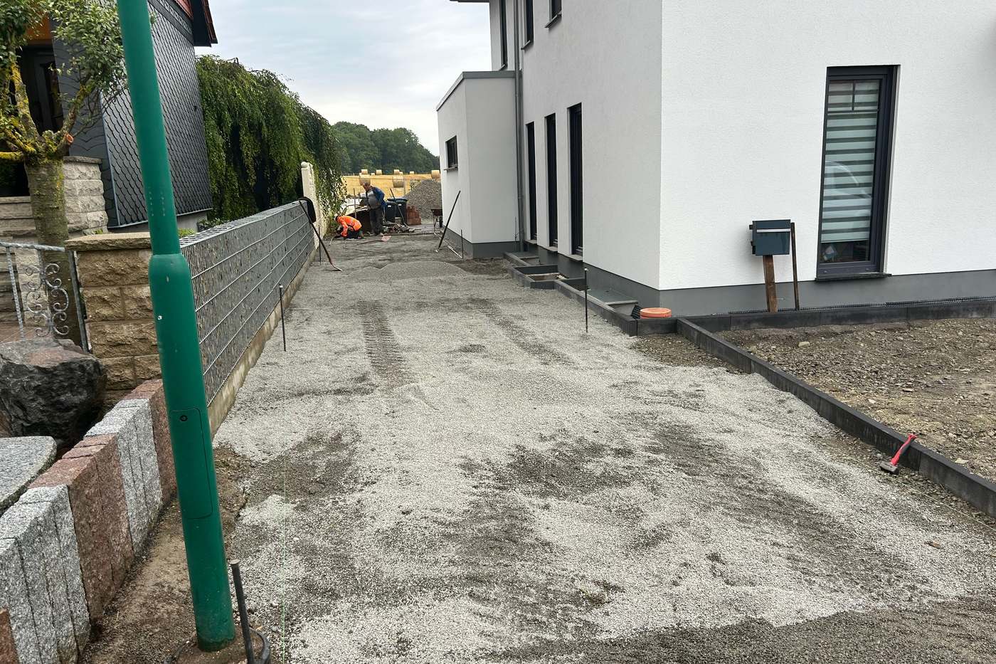 Abgezogenes Planum einer Zufahrt zwischen zwei Häusern, vorbereitet für den Pflasterbau