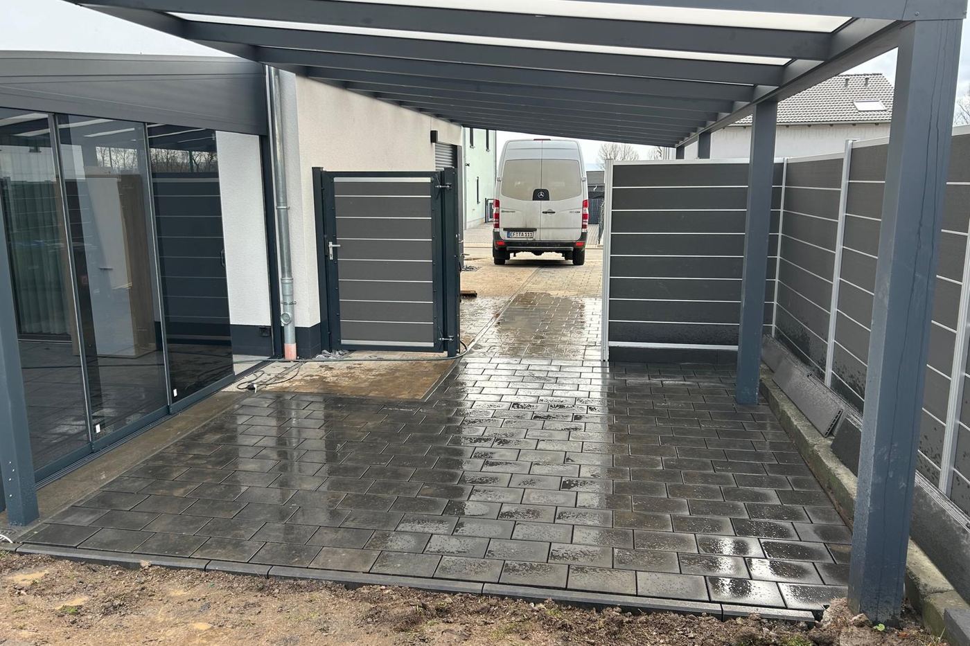 Fertig gepflasterte Fläche unter einem Carport, an den Sichtschutz herangearbeitet