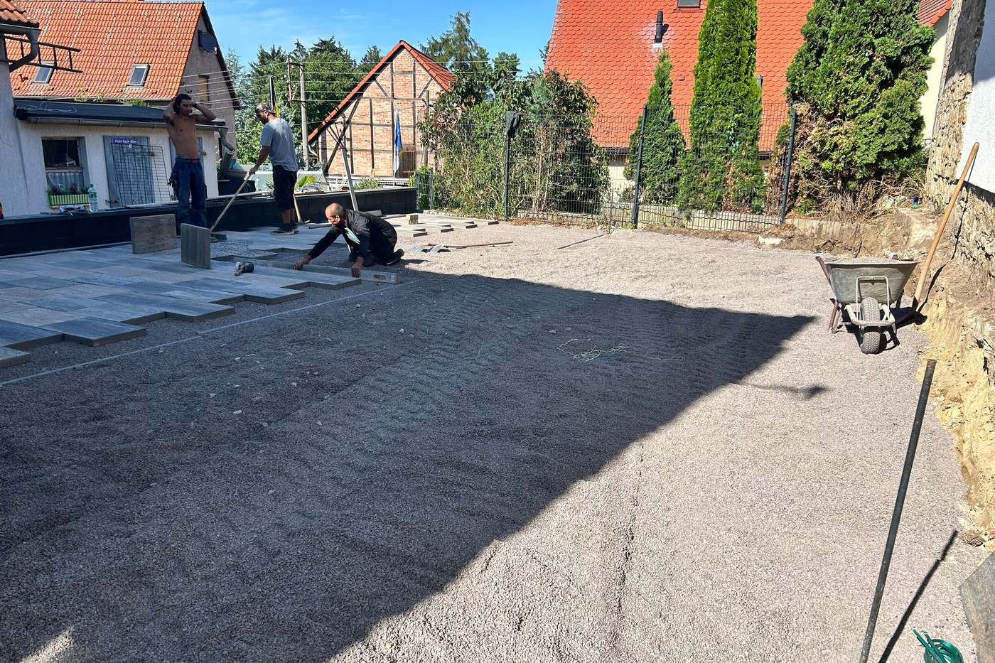 Großformatige Platten werden im Splittbett auf einem vorbereiteten Hof verlegt