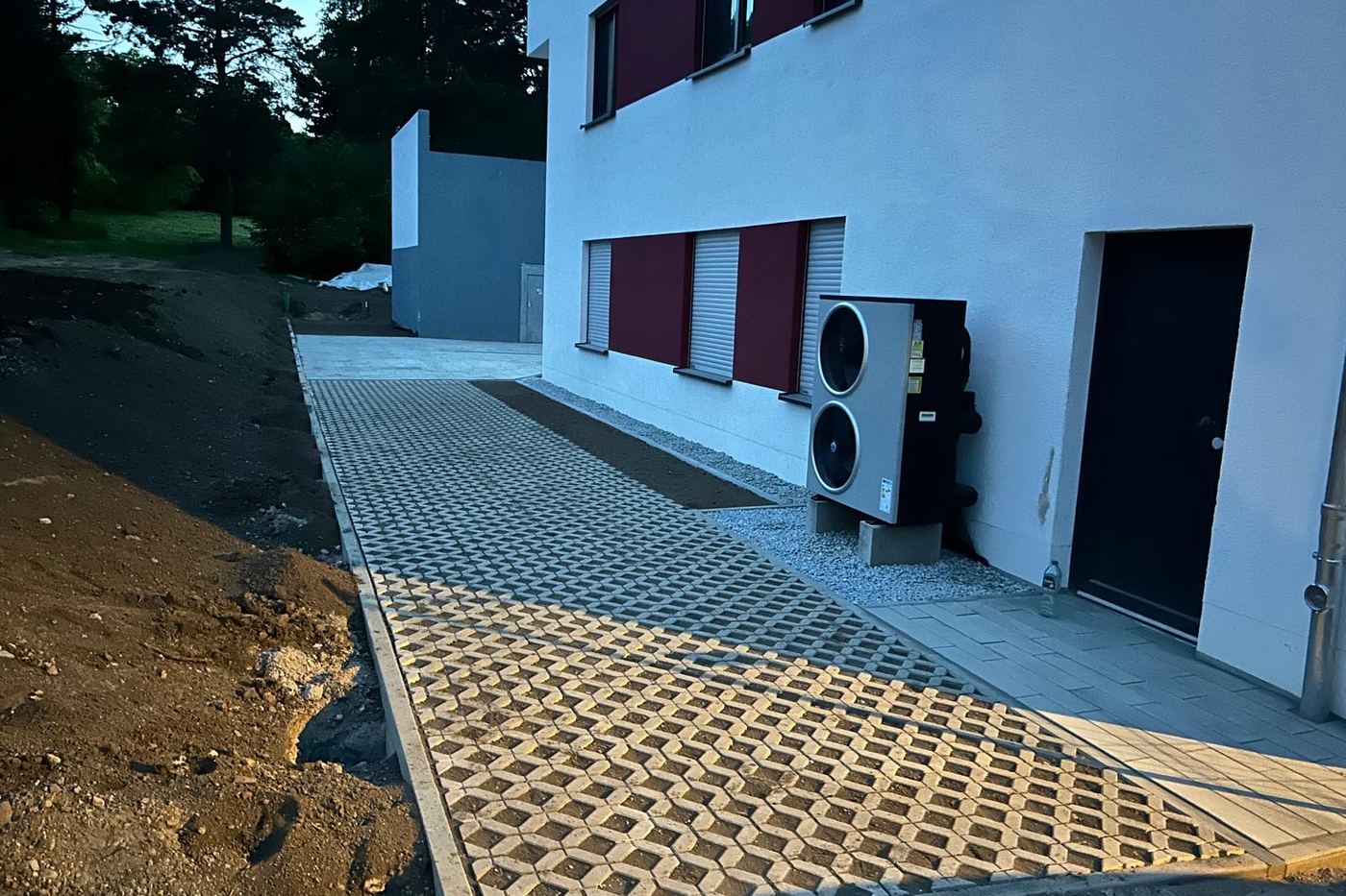 Zufahrt aus Rasengittersteinen an einem Neubau, seitlich mit Plattenweg abgesetzt