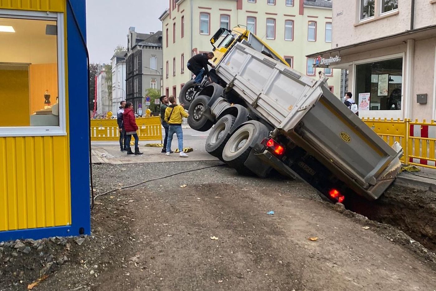 Kipper, der mit der Hinterachse in einen ungesicherten Graben eingebrochen ist und die Straße blockiert