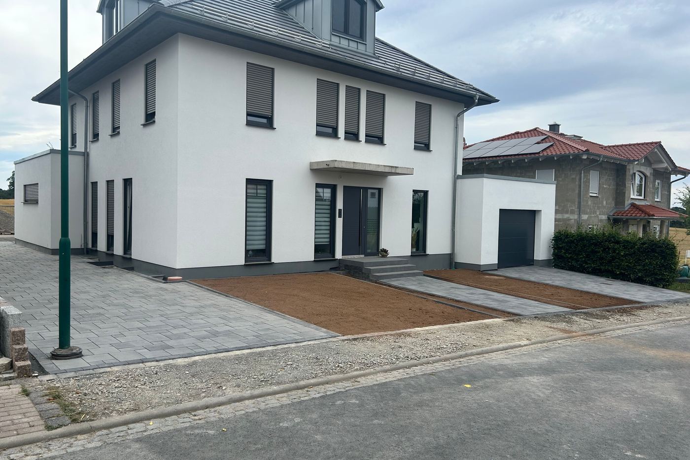 Fertiggestellte Zufahrt und Gehwegfläche an einem Neubau mit Anschluss an die Straße