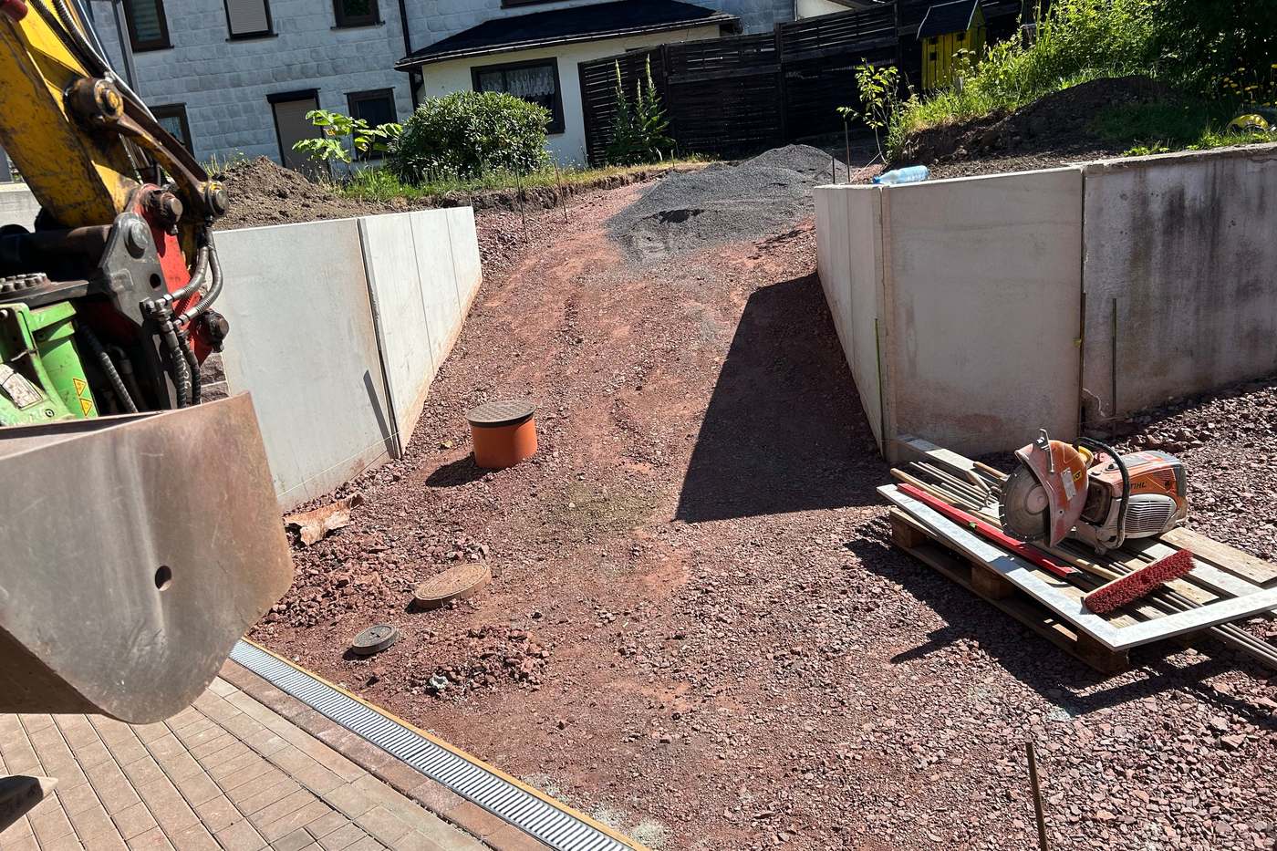Gesetzte Betonstützmauern aus L-Steinen mit Baggerlöffel im Vordergrund