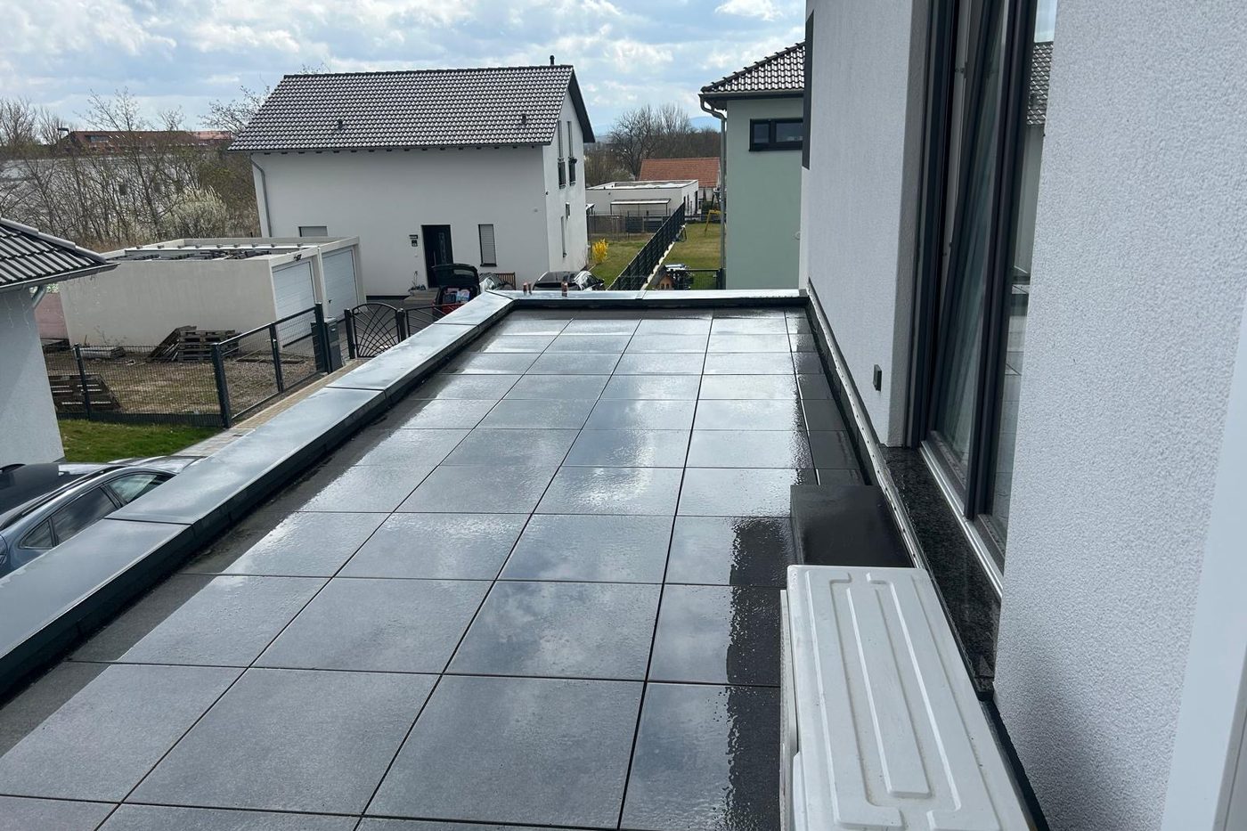 Plattenbelag einer Dachterrasse nach dem Regen, sauber an die Fassade angearbeitet
